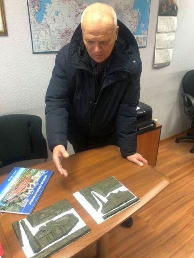 Скульптор Валентин Медведев показывает экскизы барельефа электростанции.