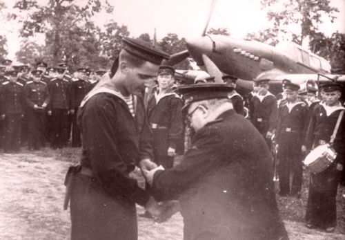 Награждение личного состава 37-го авиаполка 12-й штурмовой авиадивизии ВВС ТОФ, отличившегося в ходе советско-японской войны, аэродром Кневичи, август 1945 года. Награды вручает начальник Политуправления ТОФ генерал-майор береговой службы Муравьев А.А., справа на фото - штурмовик Ил-2 (из фондов Государственного архива Приморского края)