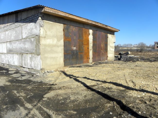 Наполовину засыпанное большое болото, на котором уже построен гараж на два бокса для большегрузных автомобилей