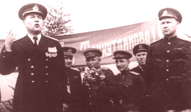 На митинге в связи с завершением освобождения Южного Сахалина выступает командующий Северной Тихоокеанской флотилией вице-адмирал В.А. Андреев. Третий слева с букетом цветом гвардии подполковник К.П. Тавхутдинов. Надпись на транспаранте «Слава отважным гвардейцам части Тавхутдинова!» (нажмите, чтобы увеличить)