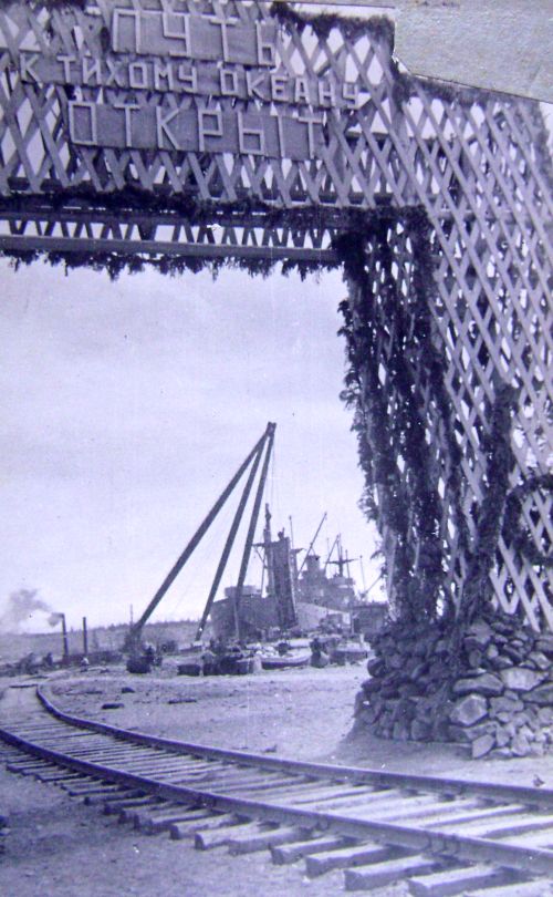 «Путь к Тихому океану открыт» изображена триумфальная арка, украшенная гирляндами цветов и флагами; за аркой хорошо просматривается морской причал и залив.  Другими словами, текстовые документы и фотоматериал однозначно говорят, что поезд, открывший сквозное движение на линии Пивань - Ванино прибыл к морскому берегу.